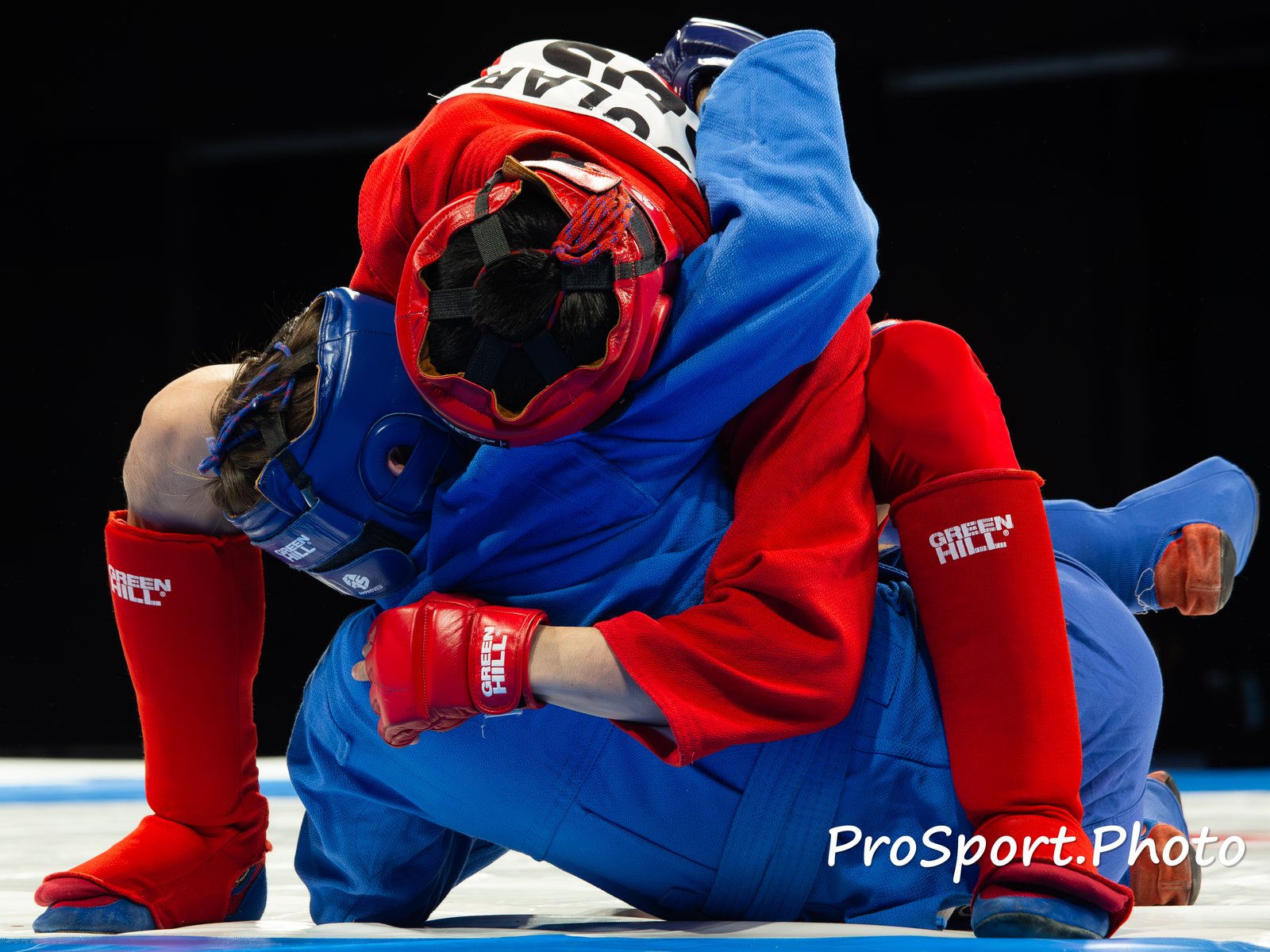 Спортсмены в красной и синей форме проводят приём на ковре. Кубок основоположников самбо — 2026.